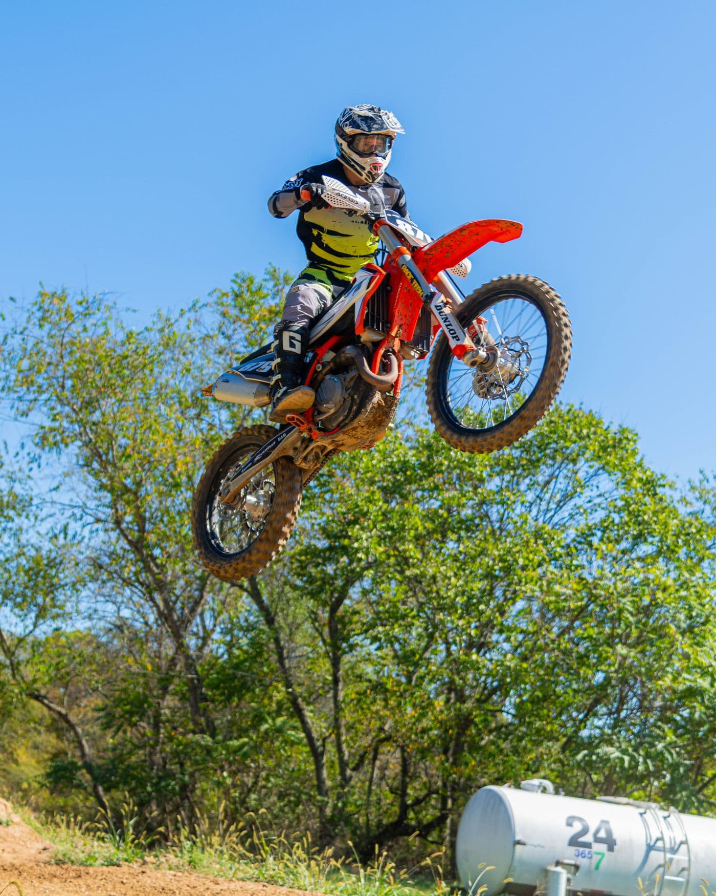 Pilote de motocross équipé, en saut au-dessus d'une piste en terre